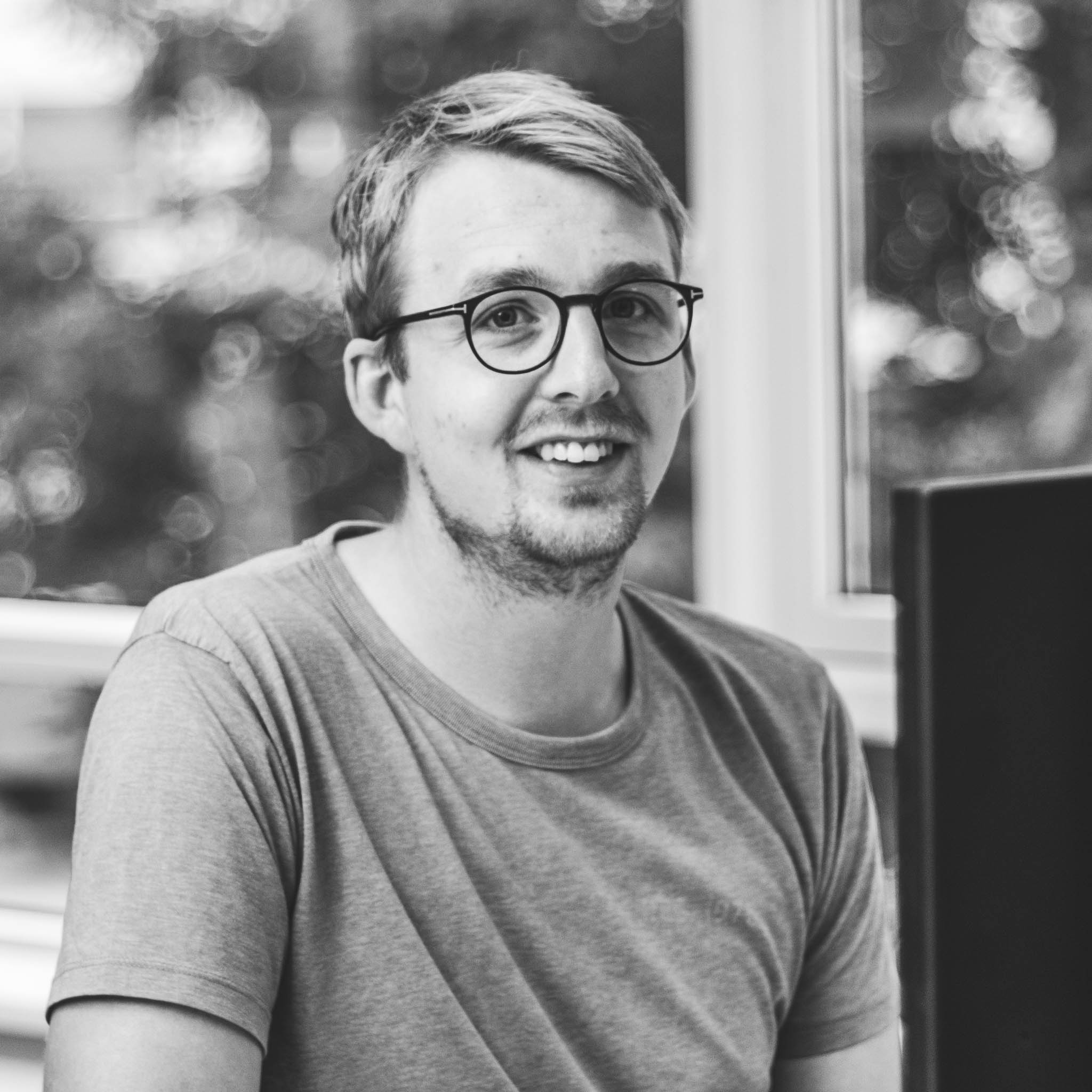 Jakob sidder ved computer med vinduer i baggrunden